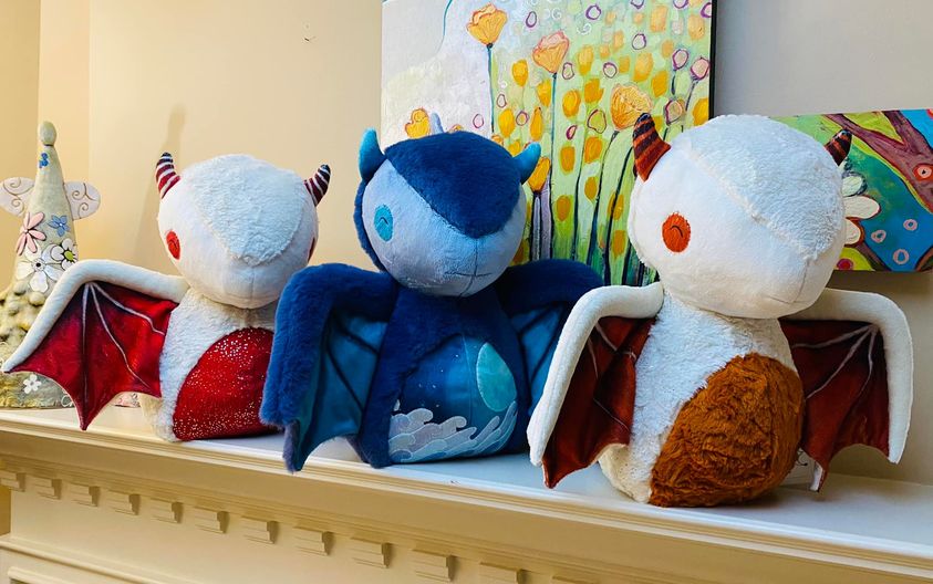 3 dragons plush toys seating on a cheminey