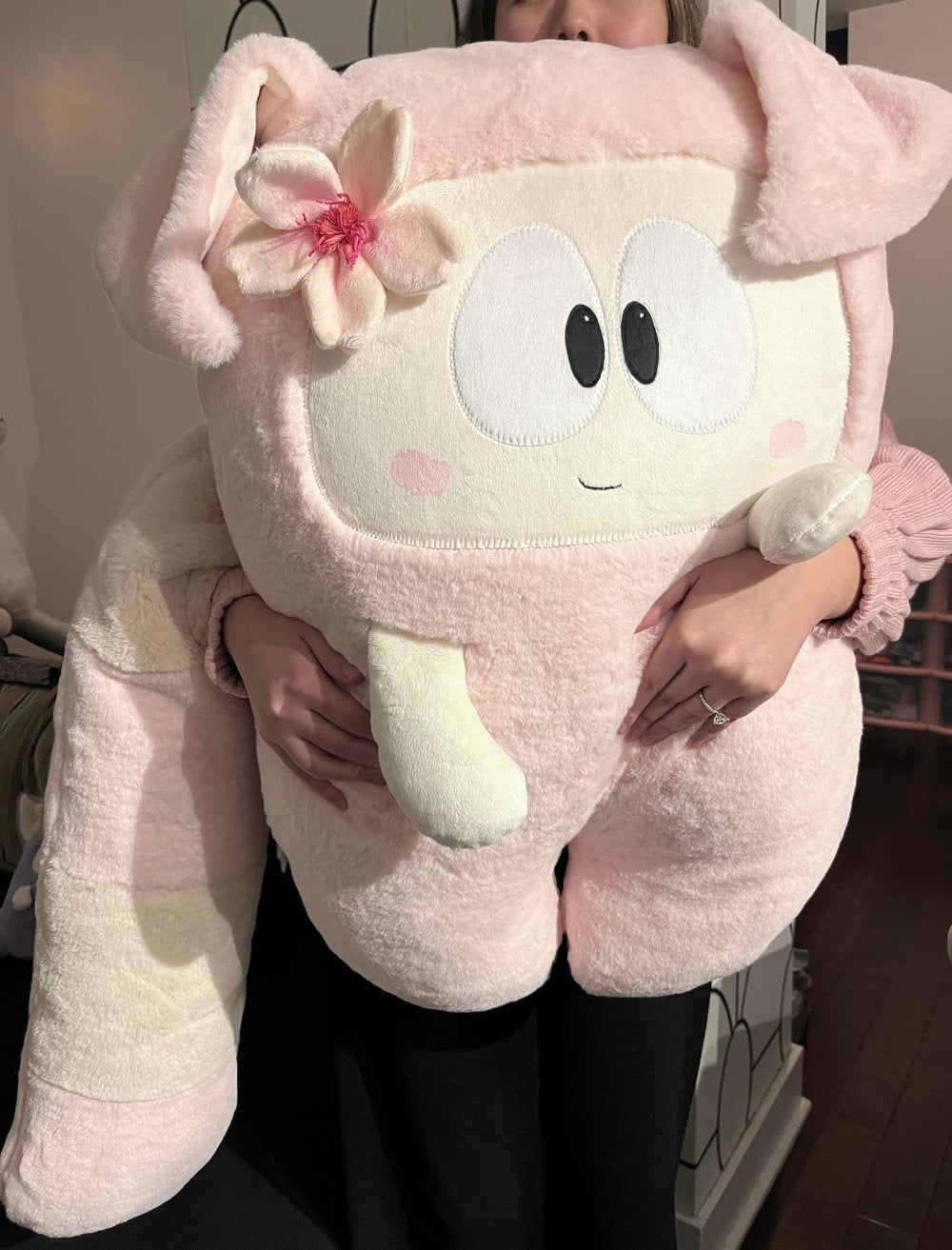 A women is holding a giant pink plush toy