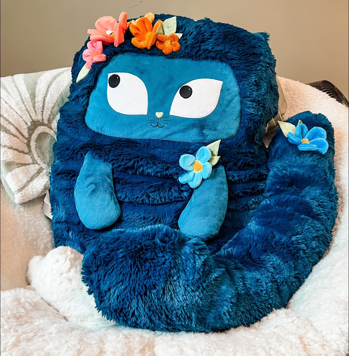 Big mallard plushie with a cat sleeping under its tail